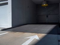 a parking garage with an arrow painted on the floor and wall to the left of the garage