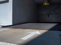 a parking garage with an arrow painted on the floor and wall to the left of the garage