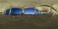 several different angles are seen in this fisheye lens image of an architectural building with arches and columns at sunset