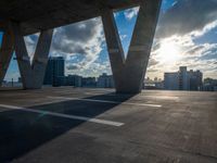 the sun shines through the clouds near a bridge with many buildings in the background