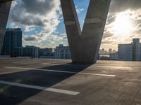 the sun shines through the clouds near a bridge with many buildings in the background