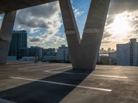 the sun shines through the clouds near a bridge with many buildings in the background