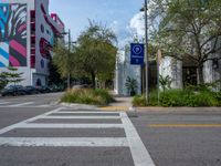 some street signs are on the side of a cross walk in an urban area with trees