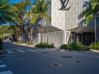 a street view of an architectural building with palm trees in the front and a yellow van parked in front