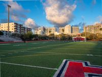 soccer field with football field markings and the stadium in the distance behind it, with apartments in the distance