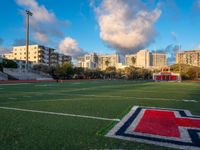 soccer field with football field markings and the stadium in the distance behind it, with apartments in the distance