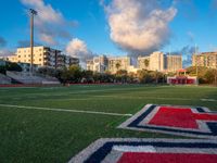 soccer field with football field markings and the stadium in the distance behind it, with apartments in the distance