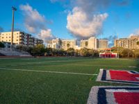 soccer field with football field markings and the stadium in the distance behind it, with apartments in the distance