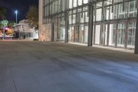 the empty sidewalk in front of the large building at night time with no lights on