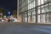 the empty sidewalk in front of the large building at night time with no lights on