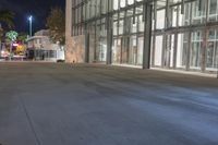 the empty sidewalk in front of the large building at night time with no lights on
