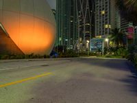 there is an image of a giant sphere on the side of the street with a lot of tall buildings behind it