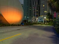 there is an image of a giant sphere on the side of the street with a lot of tall buildings behind it