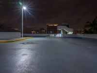 a photo at night with a car park with a light pole nearby and large buildings