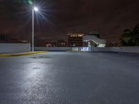 a photo at night with a car park with a light pole nearby and large buildings