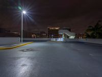 a photo at night with a car park with a light pole nearby and large buildings