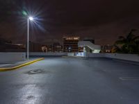 a photo at night with a car park with a light pole nearby and large buildings