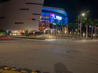 the view of an outside mall with cars coming in and out of it at night