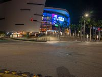 the view of an outside mall with cars coming in and out of it at night