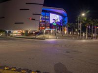 the view of an outside mall with cars coming in and out of it at night