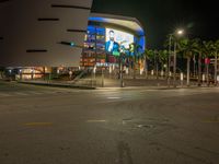 the view of an outside mall with cars coming in and out of it at night