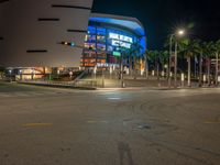 the view of an outside mall with cars coming in and out of it at night