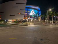 the view of an outside mall with cars coming in and out of it at night