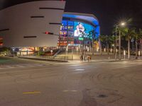 the view of an outside mall with cars coming in and out of it at night