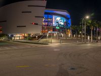 the view of an outside mall with cars coming in and out of it at night