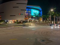 the view of an outside mall with cars coming in and out of it at night