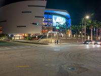 the view of an outside mall with cars coming in and out of it at night