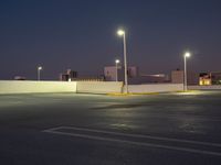 a parking lot at night with lights illuminating on it's edges and an apartment building in the background