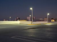 a parking lot at night with lights illuminating on it's edges and an apartment building in the background