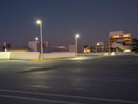 a parking lot at night with lights illuminating on it's edges and an apartment building in the background