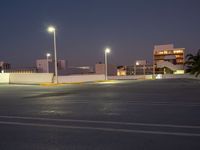 a parking lot at night with lights illuminating on it's edges and an apartment building in the background