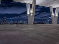 a large concrete structure with lights shining off it at night against a backdrop of tall skyscrapers