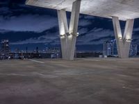 a large concrete structure with lights shining off it at night against a backdrop of tall skyscrapers