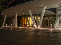 the exterior of a building in a city at night with lit street lights in the front and the entrance,