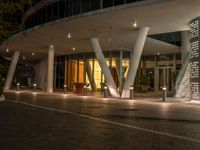 the exterior of a building in a city at night with lit street lights in the front and the entrance,