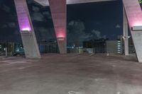 this image shows the view of a parking garage and city lights in the distance, in a darkened environment