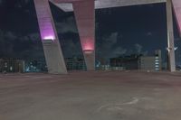 this image shows the view of a parking garage and city lights in the distance, in a darkened environment