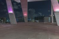 this image shows the view of a parking garage and city lights in the distance, in a darkened environment