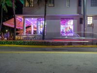 a building with bright lit windows and palm trees at night on a street in miami, usa