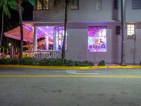 a building with bright lit windows and palm trees at night on a street in miami, usa