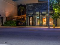 the night view of an empty road with a building in the background at dusk on a city street