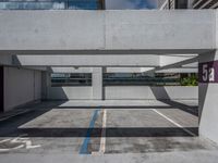 a parking garage with several buildings on the far side and trees on the other side