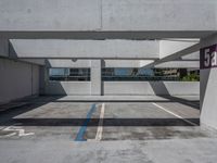 a parking garage with several buildings on the far side and trees on the other side