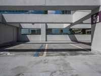 a parking garage with several buildings on the far side and trees on the other side