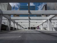 an empty parking garage between two large buildings of a skyscraper type, and in which there are columns and a blue sky