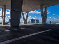 a parking garage with concrete columns and some sky in the background of this photo there are clouds